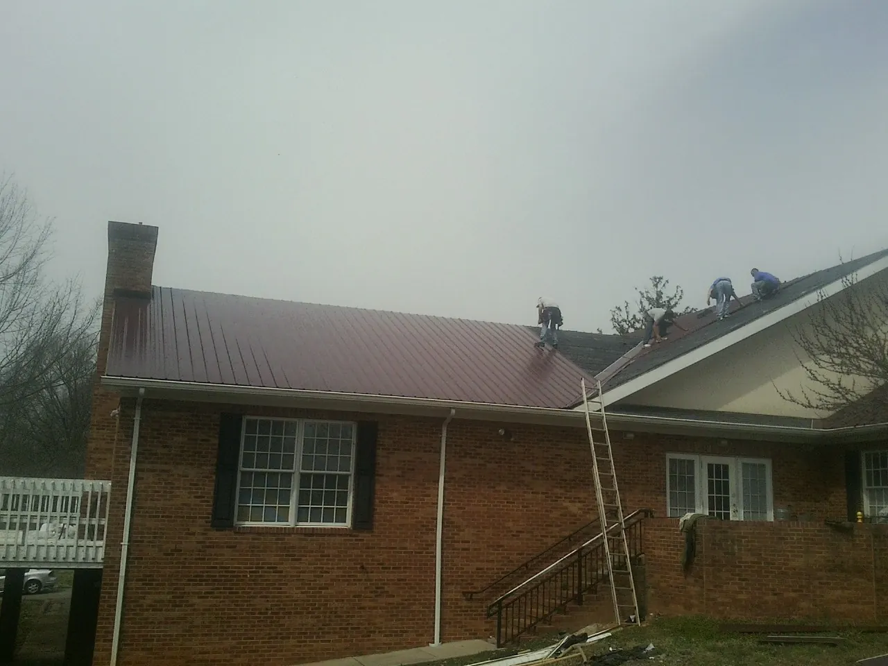 Crew setting red metal roofing panels on a brick home in Brooksville