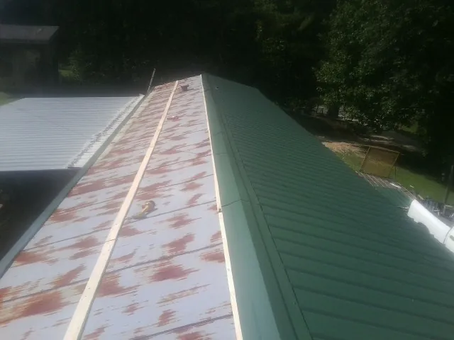 Old rusted panels beside newly installed green metal roofing — Wind Damage Roof Repair by Roofing Brothers in Brooksville